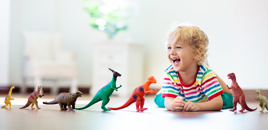 Child Playing With Toy Dinosaurs While Parents Explain Autism to Friends. 