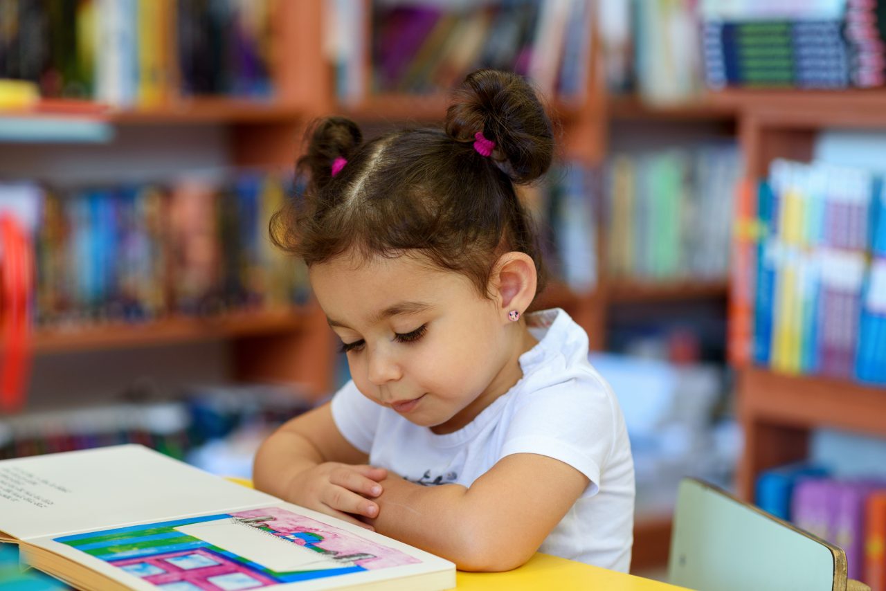 A child reading an adapted book in a special ed classroom.